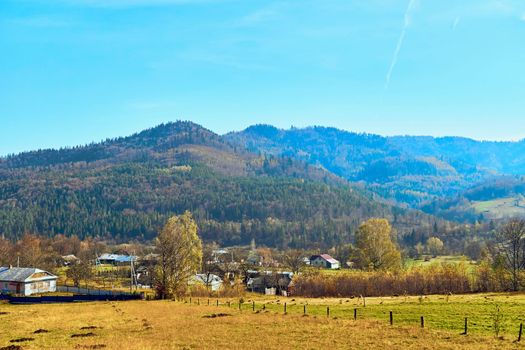 Autumn is one of the four temperate seasons. Outside the tropics, autumn marks the transition from summer to winter. Small village with fields at the foot of the autumn mountains