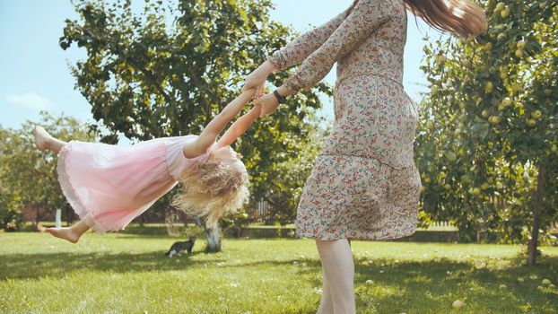 A mother circles her daughter in the garden outside the house