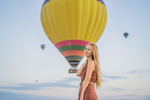 Tourist woman looking at hot air balloons in Cappadocia, Turkey. Happy Travel in Turkey concept. Woman on a mountain top enjoying wonderful view.