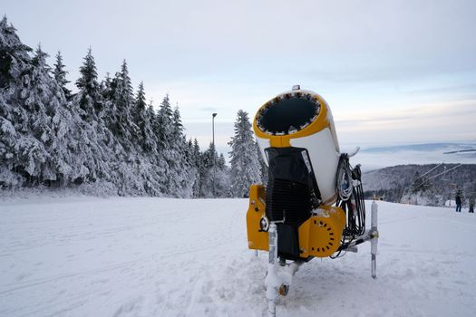 Yellow artificial snow cannon on Wasserkuppe ski resort in Rhoen Hesse Germany, on snowy mountain after fresh snow fall in 2022 december. High quality photo