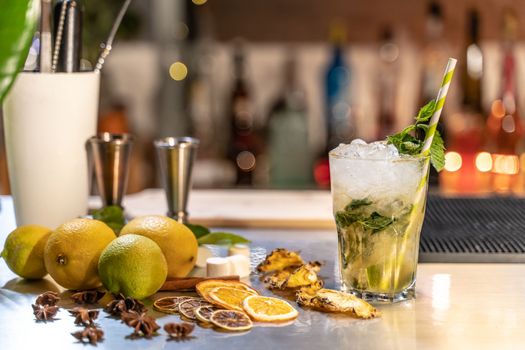 Mojito cocktail on bar counter with lemons, limes and species with copy space for text. High quality photo