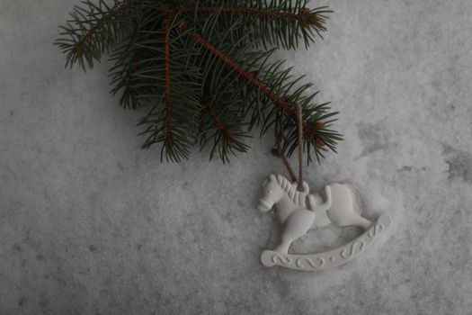 Christmas toy horse hanging on a green branches in the snow in winter. Christmas tree, toy horse, gift. New Year decor.