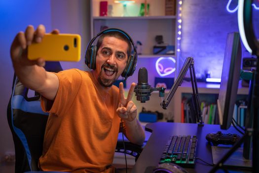 Gamer taking a selfie in gaming room playing online streaming games. High quality photo