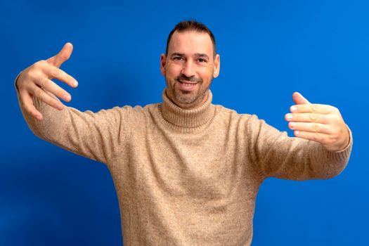 Free hugs for the person who had a bad day. Cheerful friendly Hispanic male model, pulling hands towards camera, wanting to hug, smiling broadly, welcoming friend to come into his arms