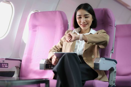 Attractive caucasian female passenger of airplane sitting in comfortable seat while working at modern laptop computer with mock up area using wireless connection