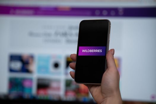 December 3, 2022, Almaty, Kazakhstan: a woman holds a smartphone with the application of wildberries on the background of the monitor