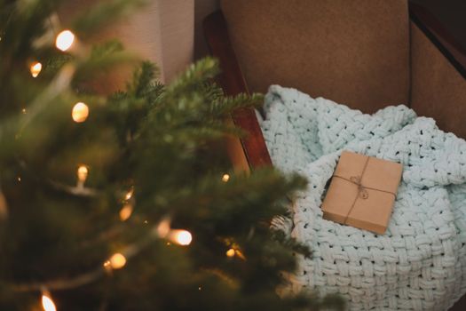 Christmas gift wrapped in craft paper under a tree. New Year card.