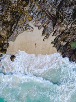 Drone aerial view at Freedom beach in Phuket Thailand, men laying down on a beach in bay at Phuket