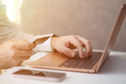 Purchases via the Internet and payment for services buy credit card. Hands type text and enter data on the laptop keyboard. An office worker checks his email while sitting at his desk