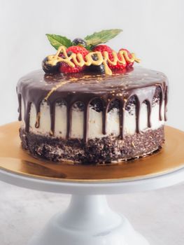 dark chocolate drips birthday sweet cake, fresh fruits Raspberry strawberry blueberry cranberry on top, decorated with golden edible paint