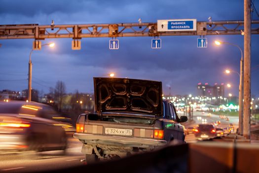 29.11.2022, Cherepovets, Russia.A large automobile bridge on which cars drive at night. There is a broken car and an emergency sign on the bridge. A bridge with large columns and lighting. 