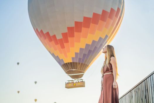 Tourist woman looking at hot air balloons in Cappadocia, Turkey. Happy Travel in Turkey concept. Woman on a mountain top enjoying wonderful view.