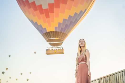 Tourist woman looking at hot air balloons in Cappadocia, Turkey. Happy Travel in Turkey concept. Woman on a mountain top enjoying wonderful view.