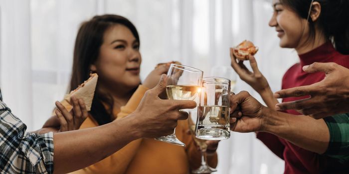 Cheers Young happy friends are toasting at the party at home. All wearing casual clothes and having fun