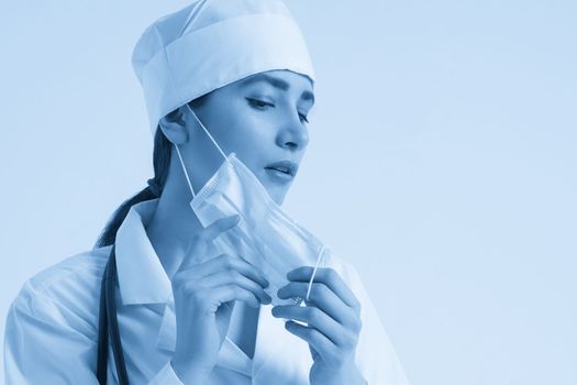 portrait of female doctor wearing protective mask and looking at camera posing against white background, copy space
