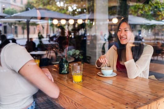 young female couple have a date over coffee and juice at a coffee shop, concept of friendship and love between women