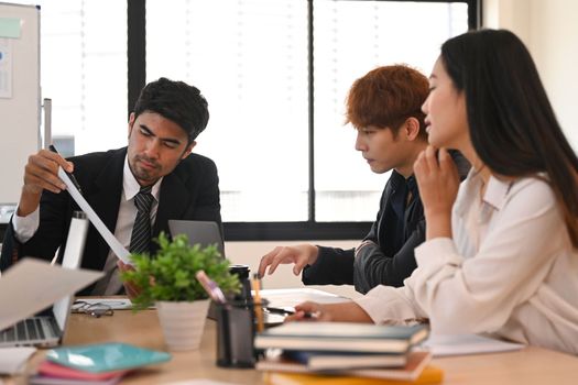 Focused male investor sharing ideas business strategy, discussing financial data with business partner at meeting.