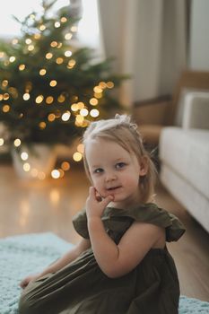 Cute little child girl and the Christmas tree indoors. Merry Christmas and Happy Holidays