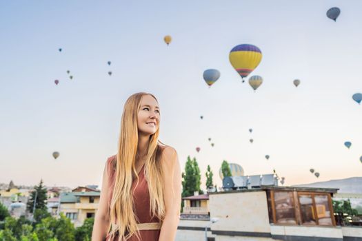 Tourist woman looking at hot air balloons in Cappadocia, Turkey. Happy Travel in Turkey concept. Woman on a mountain top enjoying wonderful view.