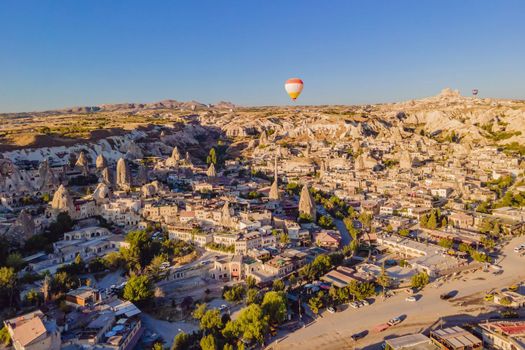 Colorful hot air balloons flying over at fairy chimneys valley in Nevsehir, Goreme, Cappadocia Turkey. Spectacular panoramic drone view of the underground city and ballooning tourism. High quality.