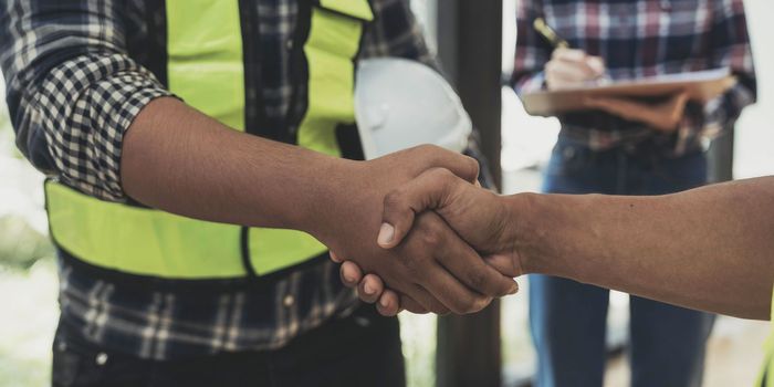 construction worker team hands shaking after consultation meeting to greeting start up plan new project contract in office center at construction site, teamwork, partnership and contractor concept..