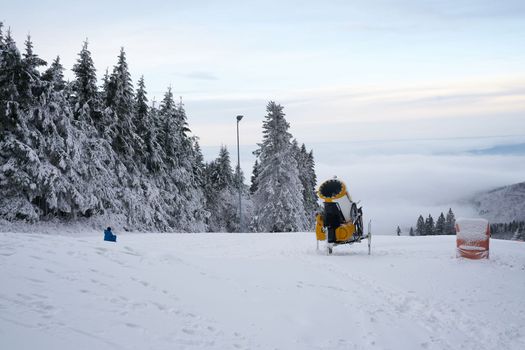 Yellow artificial snow cannon on Wasserkuppe ski resort in Rhoen Hesse Germany, on snowy mountain after fresh snow fall in 2022 december. High quality photo