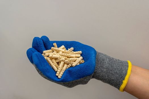 A worker's hand in a protective glove holds a bunch of plastic dowel pins on a white background. renovation in the bathroom. installation of bathroom accessories.