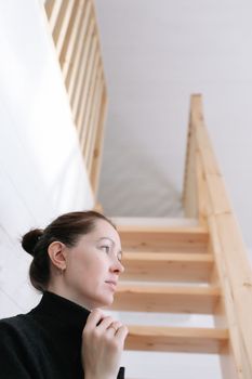 Young woman simple hairstyle against wooden stairs. Depression, loneliness and quarantine concept. Mental health, Self care, staying home