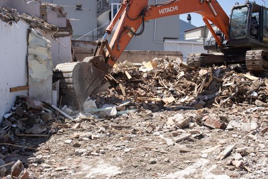 Urla, Turkey - may 13, 2020 excavator loading debris of a destroyed building in truck.