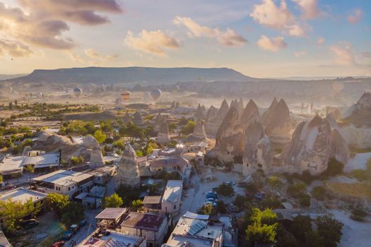 Colorful hot air balloons flying over at fairy chimneys valley in Nevsehir, Goreme, Cappadocia Turkey. Spectacular panoramic drone view of the underground city and ballooning tourism. High quality.