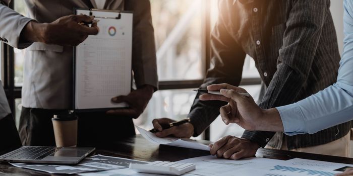 Business People Meeting using laptop computer,calculator,notebook,stock market chart paper for analysis Plans to improve quality next month. Conference Discussion Corporate Concept...