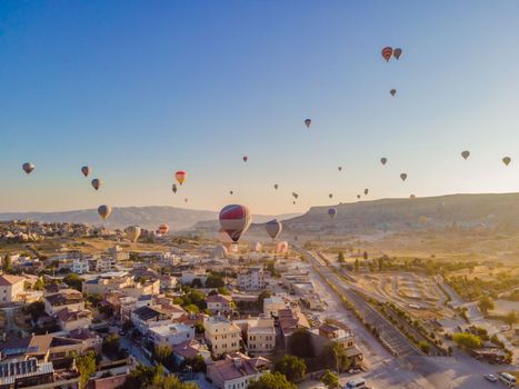 Colorful hot air balloons flying over at fairy chimneys valley in Nevsehir, Goreme, Cappadocia Turkey. Spectacular panoramic drone view of the underground city and ballooning tourism. High quality.