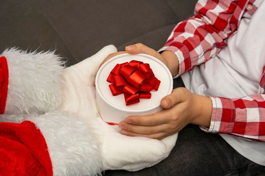 Santa gives a Christmas gift to a child. Santa's hands are holding a beautiful gift box. Christmas time. Merry Christmas and Happy New Year. 