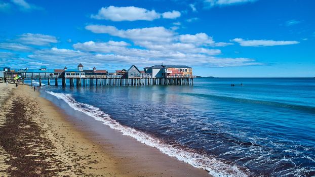 Image of Beach views in Maine with waves crashing and old wood pier covered in shops
