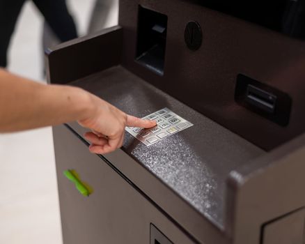 Faceless woman dialing bank card pin at ATM
