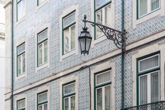 Ancient Portuguese building, covered with blue patterned azulejo tile and with a wrought-iron lantern on the wall background