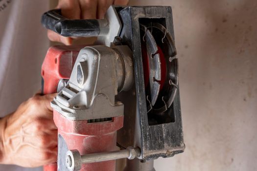 professional construction power tool for cutting grooves in concrete in the hands of a worker during the renovation of the apartment. A hand-held power tool with two diamond discs for cutting grooves in the wall for laying electrics. Professional tool. Close-up