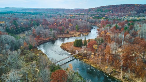 Image of Late fall aerial over Michigan river with suspension bridge and fall colors