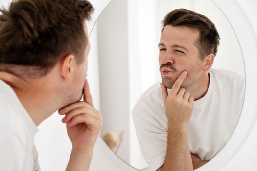 Selfish young caucasian man trying to cheer himself up before a first date looking at the mirror 