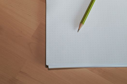 Paper sheet with a pencil on wooden table. Pencil on table, the blogger instrument