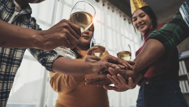 Cheers Young happy friends are toasting at the party at home. All wearing casual clothes and having fun