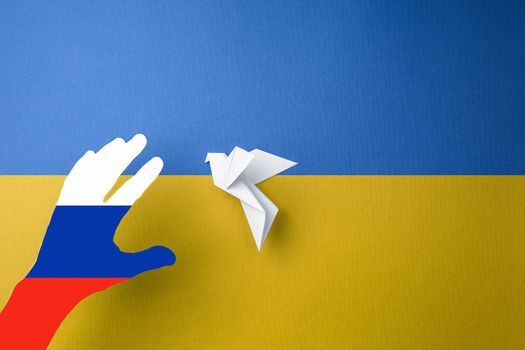terror and annexation in ukraine, hand painted in colors of the russian flag catches dove bird of freedom in ukraine, yellow blue background. concept needs help and support, truth will win