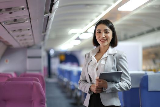 Attractive caucasian female passenger of airplane sitting in comfortable seat while working at modern laptop computer with mock up area using wireless connection