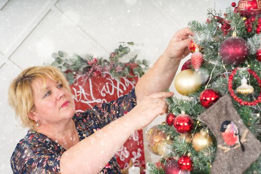 Woman decorating beautiful Christmas tree with ornamets at home, closeup. christmas holidays and people concept. Christmas atmosphere