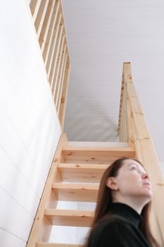 Young woman simple hairstyle against wooden stairs. Depression, loneliness and quarantine concept. Mental health, Self care, staying home