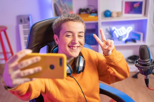 Gamer girl with short haircut taking a selfie playing online games and streaming. High quality photo