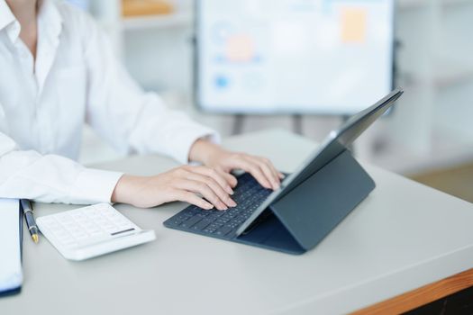 Portrait of a thoughtful Asian businesswoman looking at financial statements and making marketing plans using a computer on her desk.