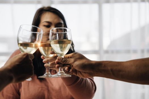 Cheers Young happy friends are toasting at the party at home. All wearing casual clothes and having fun