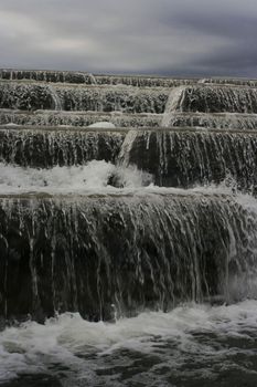 Waterfall in cloudy weather against the background of the sky.