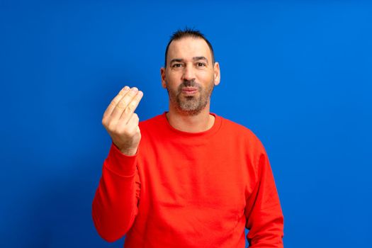 Handsome latino man with beard making a typical italian gesture, smiling and looking to the front, symbol or expression with his hand, very natural